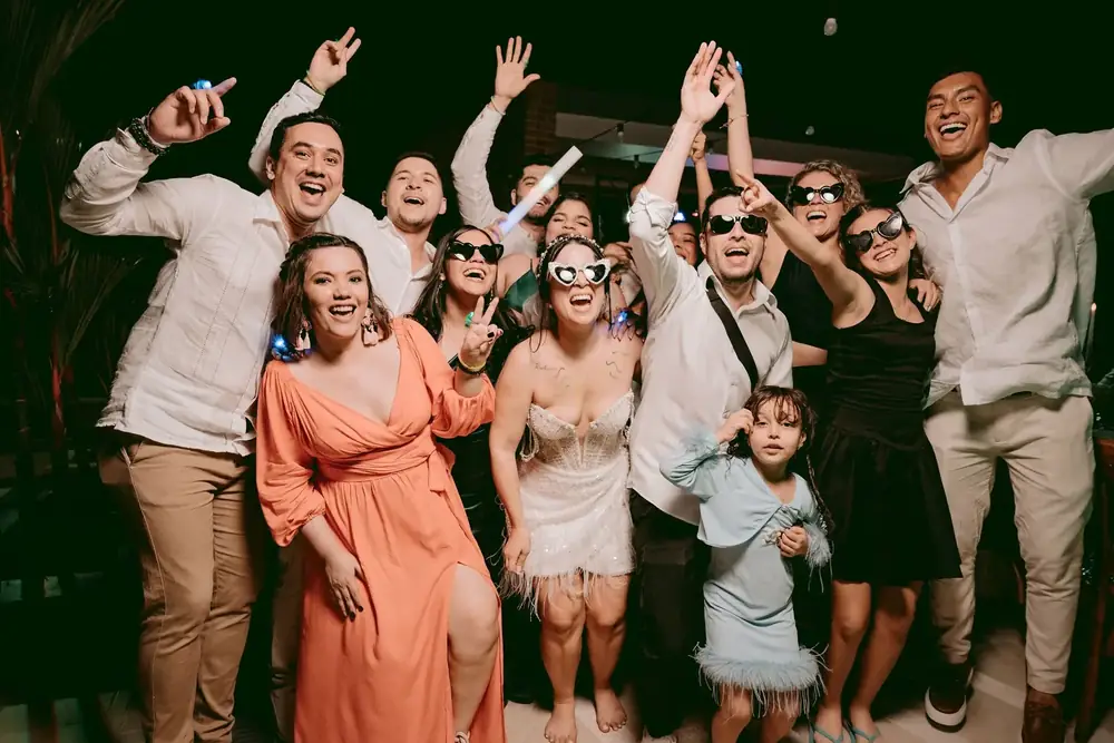 Invitados de una boda con gafas de corazón celebrando en la pista